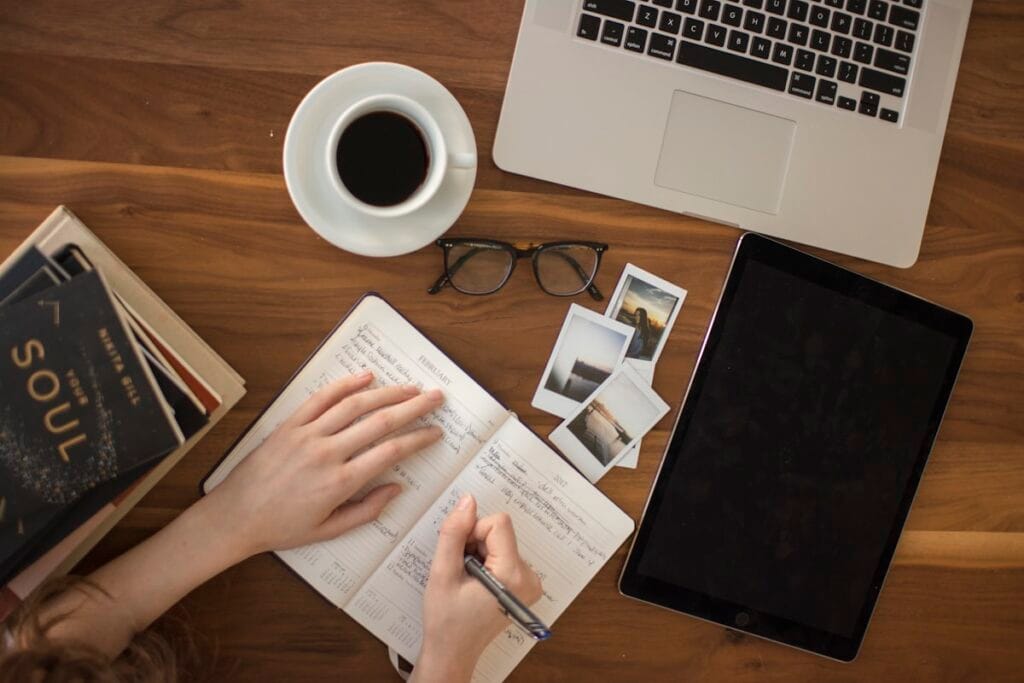 Tableau de travail avec ordinateur, carnet, café et photos.