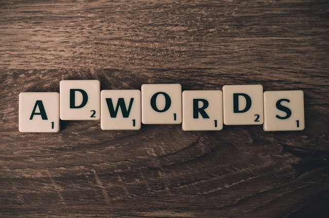 Mots clés 'ADWORDS' en blocs de Scrabble sur une surface en bois.