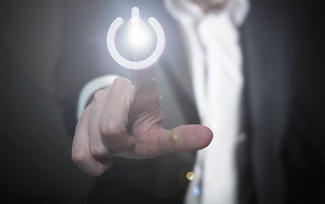 Person appuyant sur un bouton d'alimentation lumineux pour démarrer un appareil.