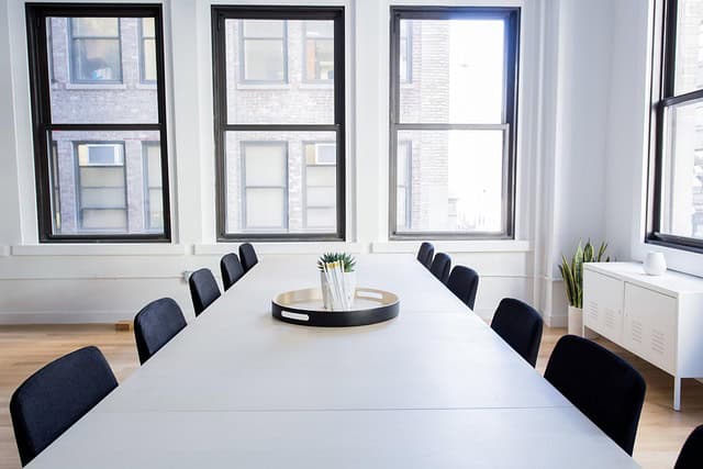 Salle de réunion moderne avec grande table et chaises noires.