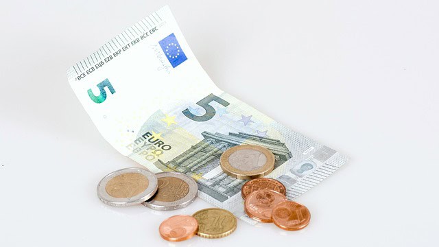 Billets de banque et pièces de monnaie euro sur fond blanc.
