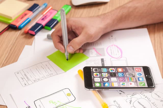 Personne qui écrit des notes et utilise un smartphone pour la planification.